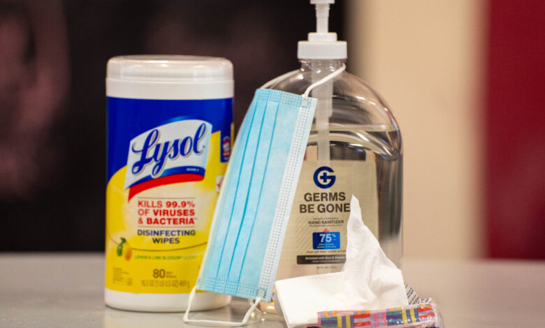 A Lysol container, hand sanitizer and mask on a table