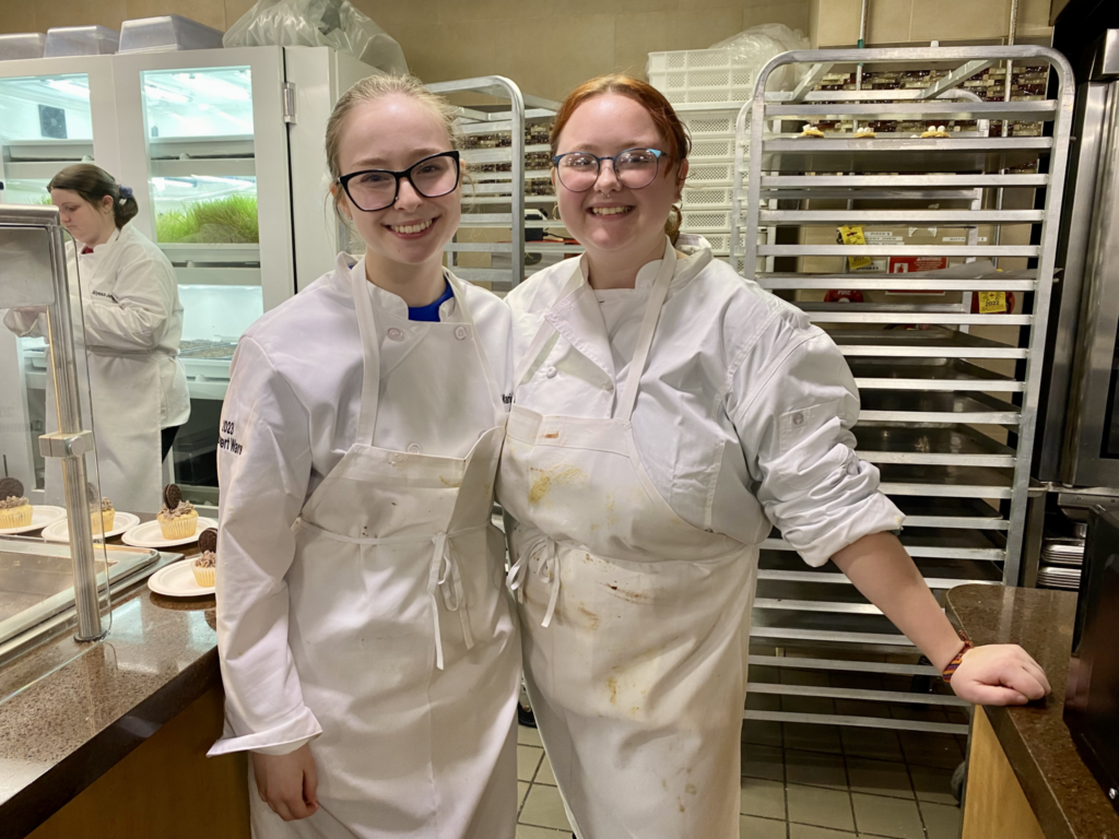 Junior English major Marissa Harding and her co-chef junior international business major Bridget Teal pose for a photo behind the counter. 