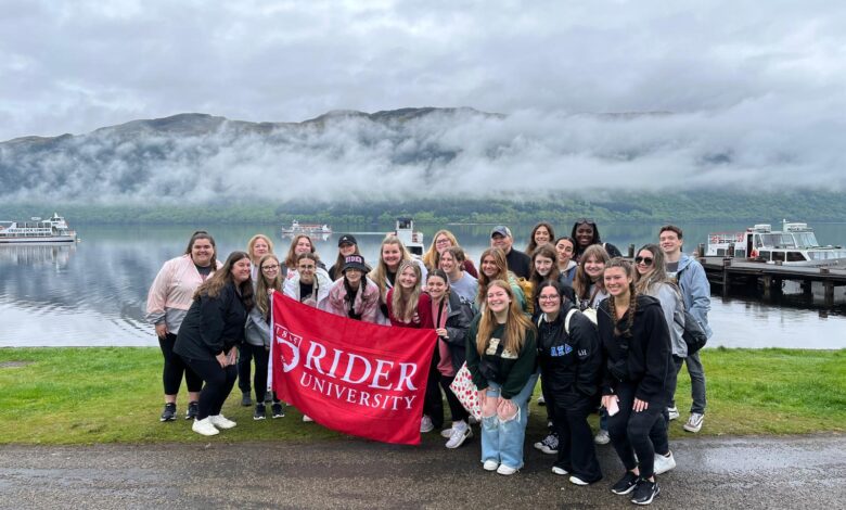 A group of students take a photo with the Rider flag in the Scottish Highlands.
