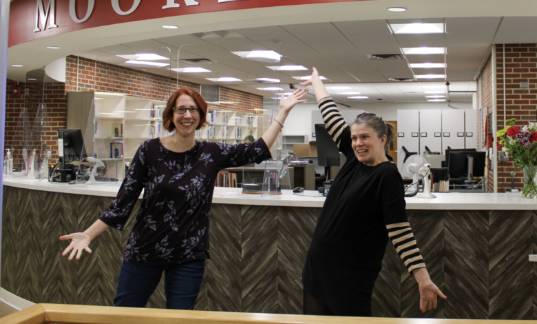 Librarians Sharon Whitfield (left) and Melissa Hofmann (right) pose in front of circulation desk in library.