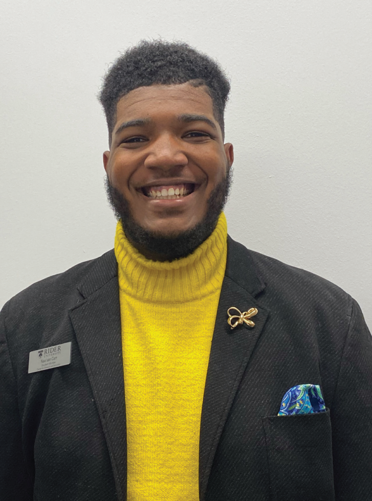 Junior political science major, Naa’san Carr, smiles for the camera in a yellow turtle neck. 
