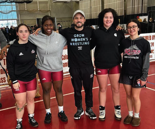 Coach Timothy Trivisonno (center) and members of the women’s
wresting club pose for a photo while at a match.