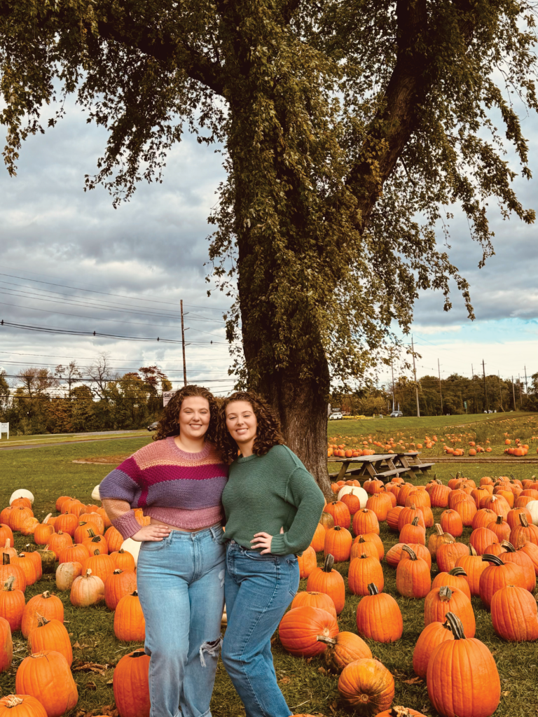 Felicia and Francesca Roehm stand in front of pumpkins