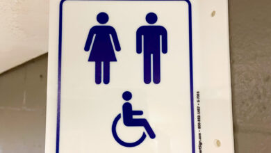 A sign featuring two genders and a person with a wheelchair is placed above the gender-inclusive/accessible bathrooms.