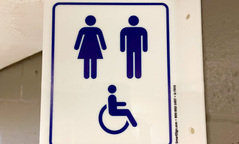 A sign featuring two genders and a person with a wheelchair is placed above the gender-inclusive/accessible bathrooms.