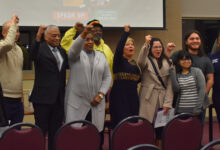 Attendees of the event stand together for a group photo and hold their fists in the air.