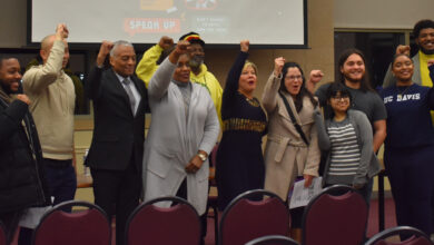 Attendees of the event stand together for a group photo and hold their fists in the air.