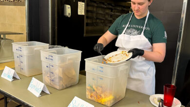Skyler O'Kelley sorts the different kinds of waste into bins labeled as liquids, paper and solids.