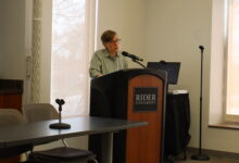 Margot Canaday gives a keynote speech on queer identities in the workplace while standing in front of a podium.