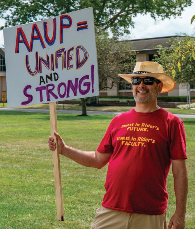 Joel Feldman, an associate professor, holds a sign saying “AAUP=Unified and strong!” 