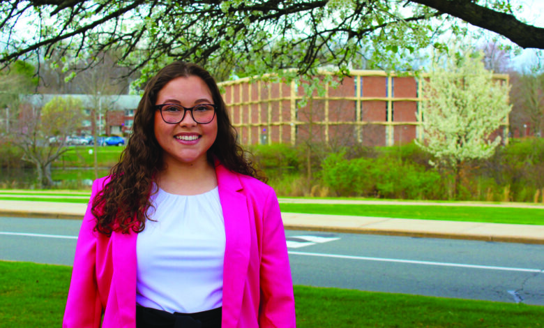 Christina Natoli, SGA presidential candidate, stands in front a tree wearing a pink blazer.
