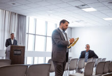 A man takes notes on a pad in front of a group of people.