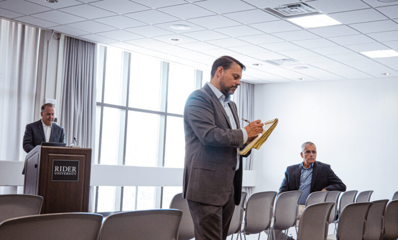 A man takes notes on a pad in front of a group of people.