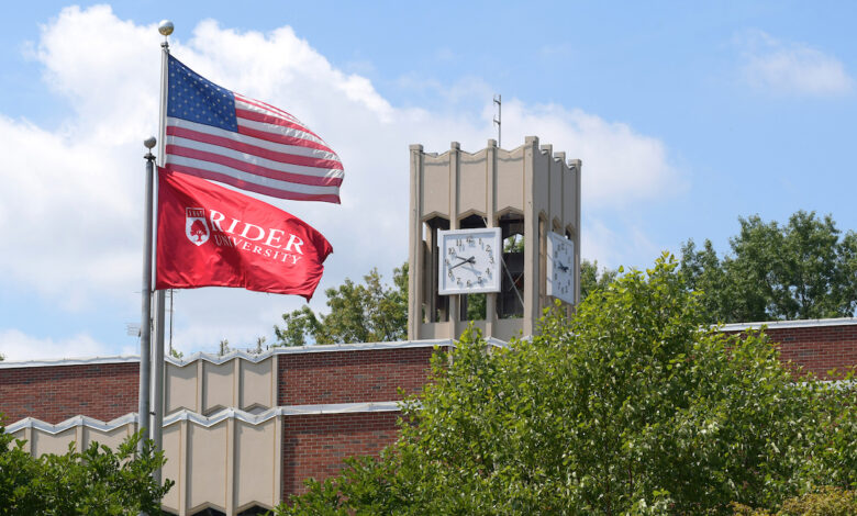 The American flag and Rider flag stand before the library at Rider University.