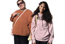 Two Rider students stand beside each other, one holding an "I voted" sticker.