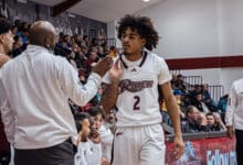 Sophomore guard Ruben Rodriguez fist bumps a coach as he heads to the bench. Photo by Josiah Thomas