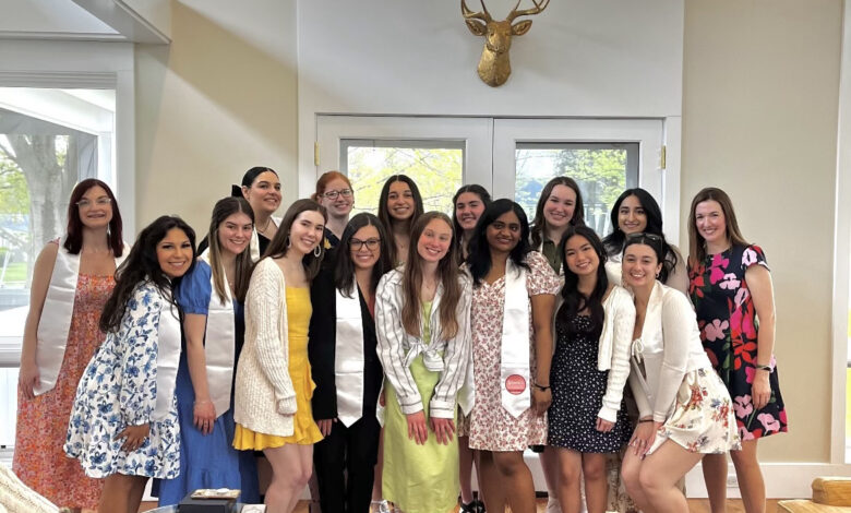 A group of women in the Gail Bierenbaum Leadership Council stand together for a picture in front of a window.