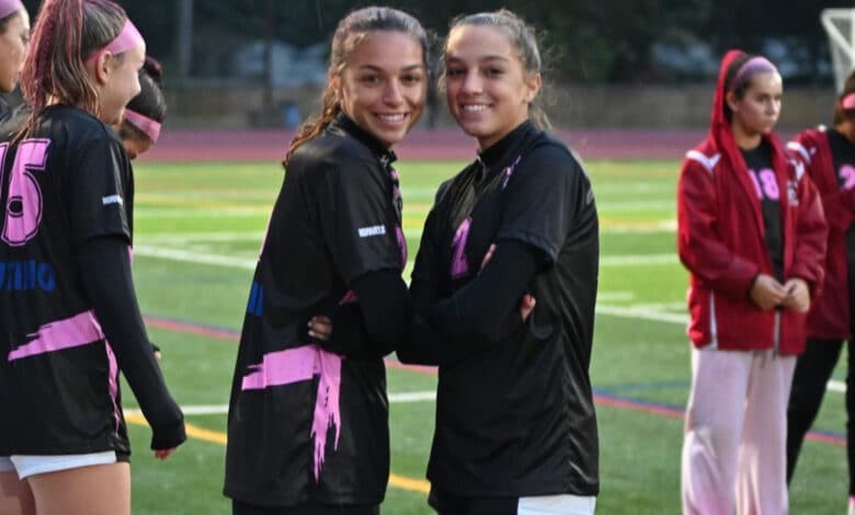 Junior forward Ava Ferrie (left) and sophomore forward Tess Ferrie (right) pose on the sidelines together.